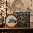Cargar la imagen en la vista de la galería, Octagonal landscape embroidery ornament displayed beside a navy blue and gold dragon pattern gift case on a wooden console table