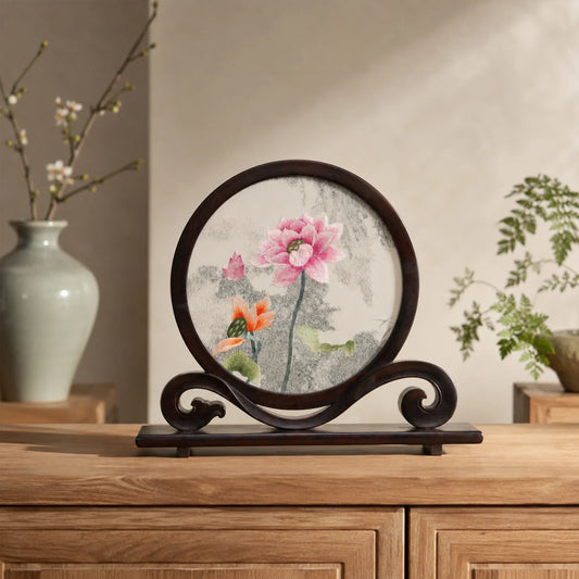 Double-sided embroidery of pink and orange lotus blossoms with green leaves in a round dark hardwood frame on a scroll-carved wooden stand