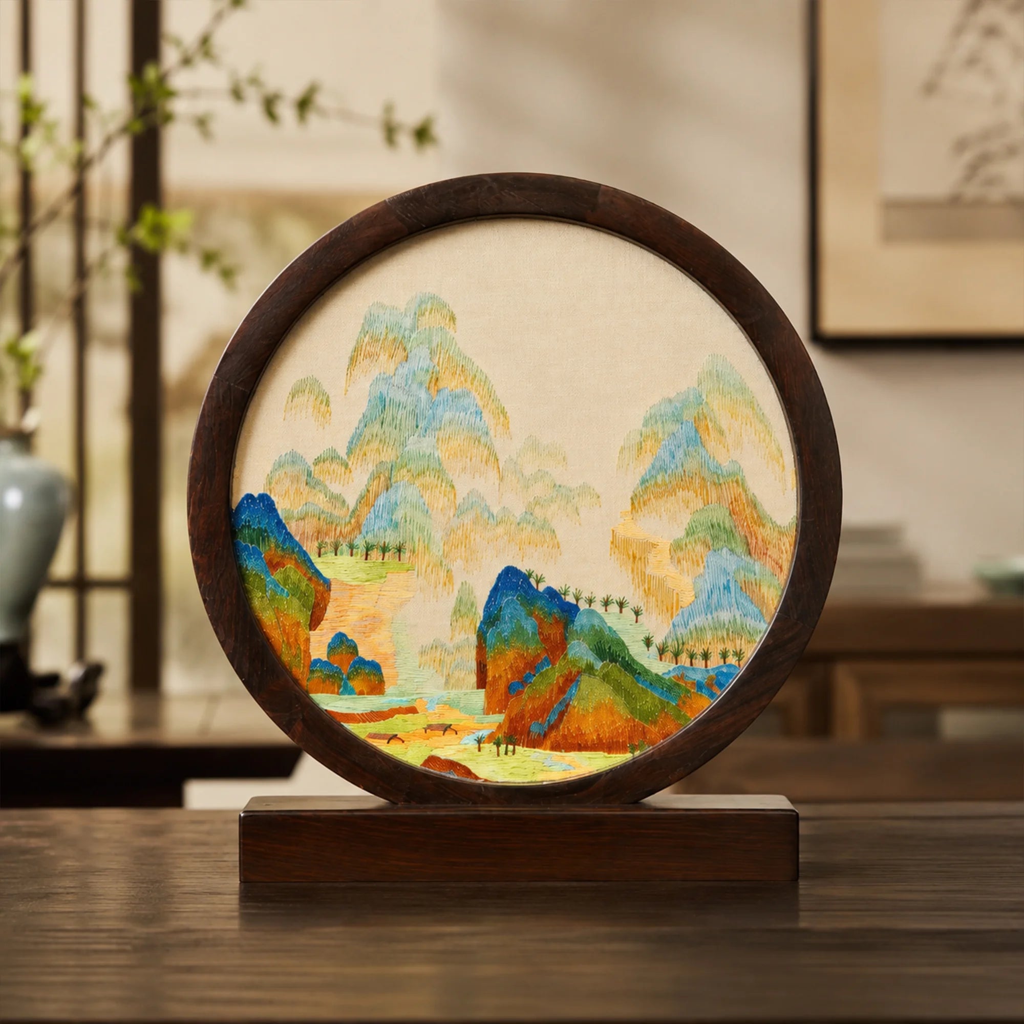Round landscape embroidery ornament displayed on a wooden console table in a traditional Chinese room setting