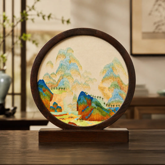 Round landscape embroidery ornament displayed on a wooden console table in a traditional Chinese room setting