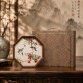 Cargar la imagen en la vista de la galería, Octagonal embroidery ornament beside a copper-toned brocade cloud-and-wave pattern carrying case on a carved wooden console

