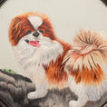 Load image into Gallery viewer, Double-sided embroidery of a brown and white Pekingese dog standing on a rock in a circular frame within a rectangular hardwood screen stand
