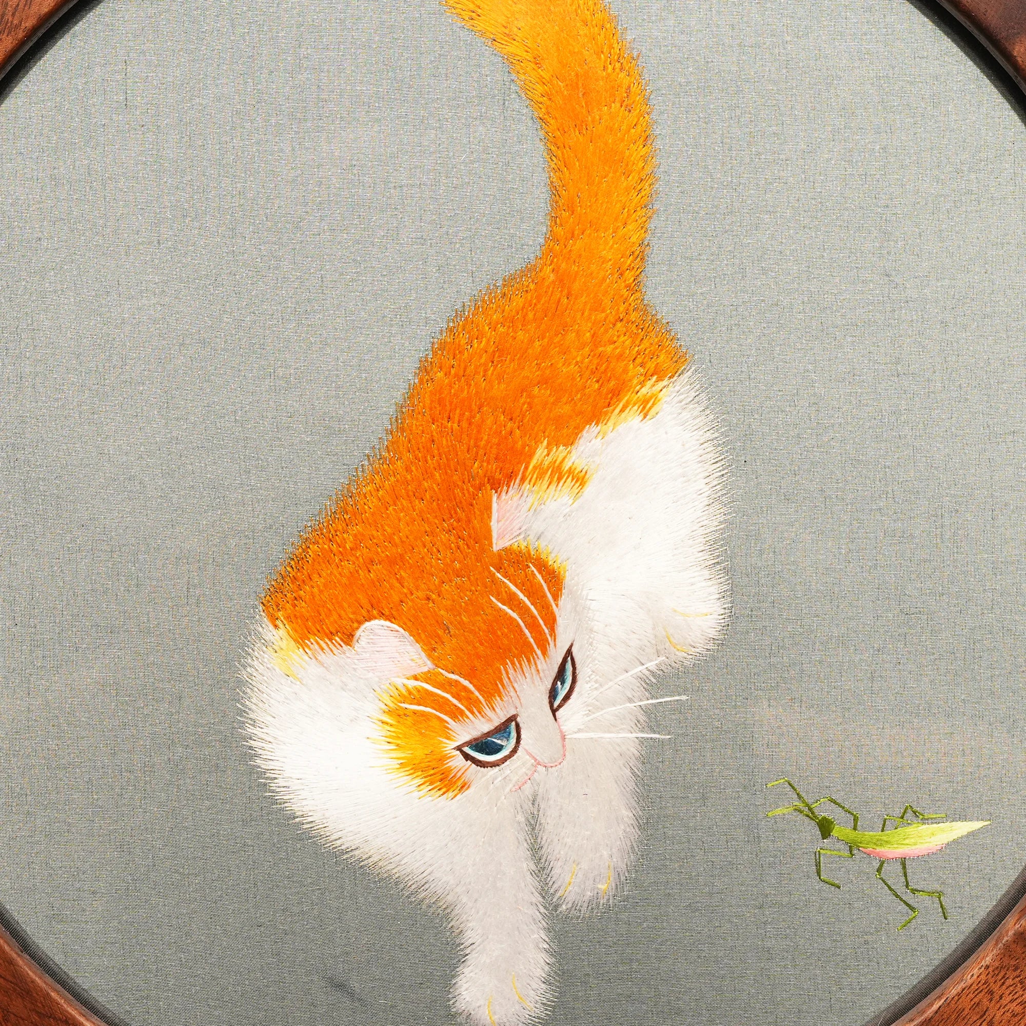 Reverse side of double-sided embroidery featuring orange and white cat in same playful pose with grasshopper on gray silk