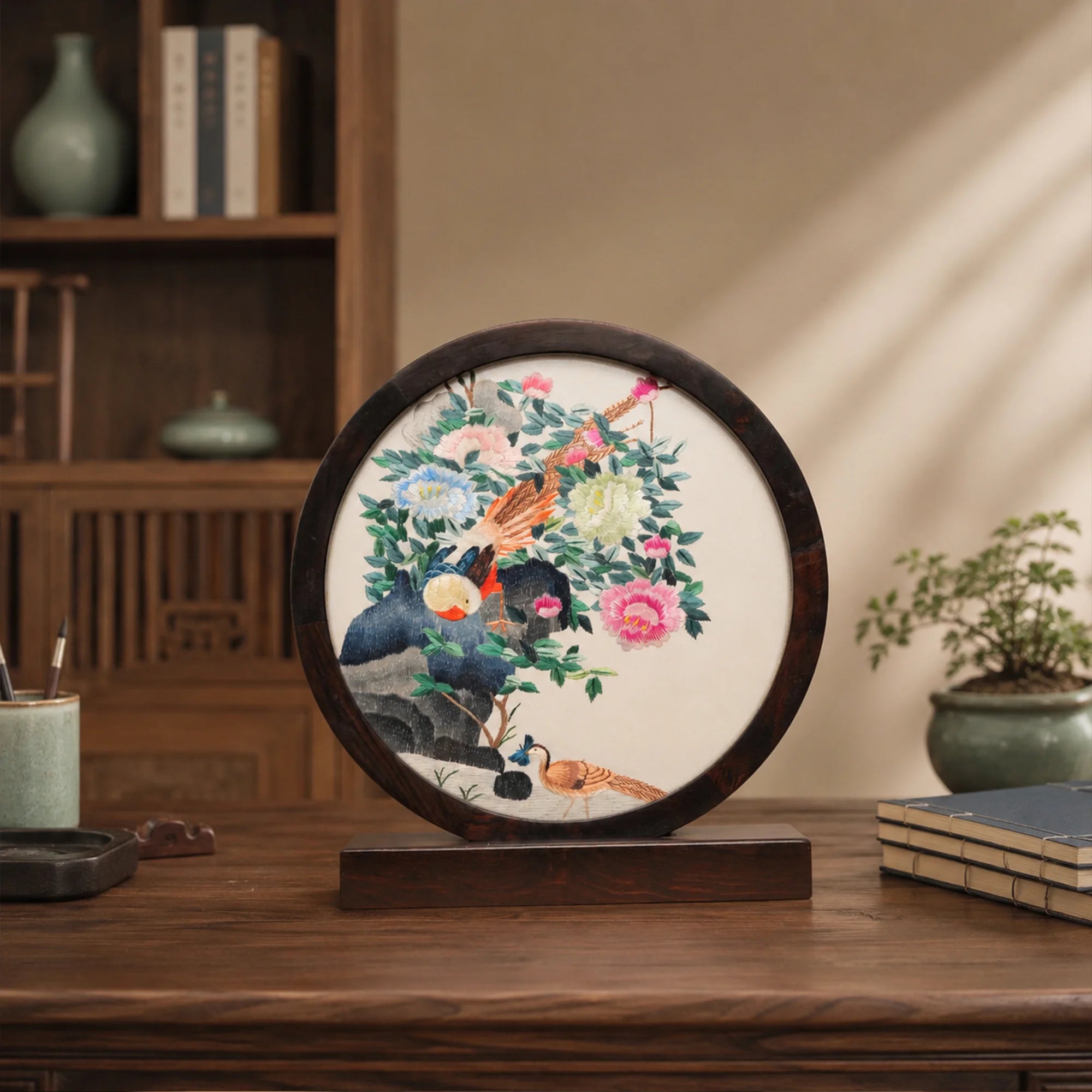 Pheasant and peony embroidery ornament on a wooden console table with a celadon vase in a softly lit traditional room
