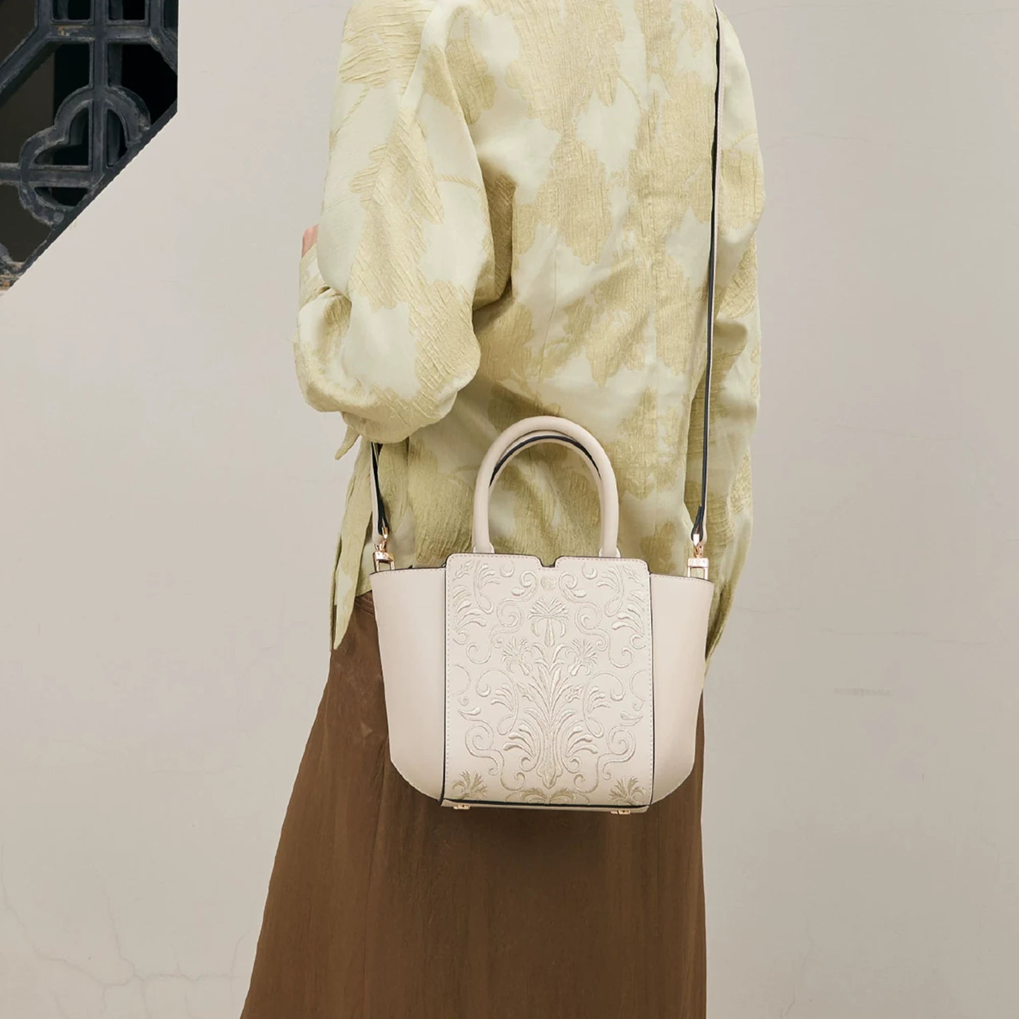 SinoCrafted Suzhou embroidery crossbody handbag with delicate floral patterns, styled by a woman in a modern Chinese-inspired setting.