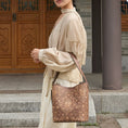 Load image into Gallery viewer, SinoCrafted brown scrolling vine embroidery tote bag styled over the shoulder, showcasing intricate Chinese-inspired embroidered details.
