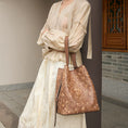 Load image into Gallery viewer, SinoCrafted brown scrolling vine embroidery tote bag styled over the shoulder, showcasing intricate Chinese-inspired embroidered details.
