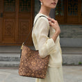 Load image into Gallery viewer, SinoCrafted brown scrolling vine embroidery tote bag styled over the shoulder, showcasing intricate Chinese-inspired embroidered details.
