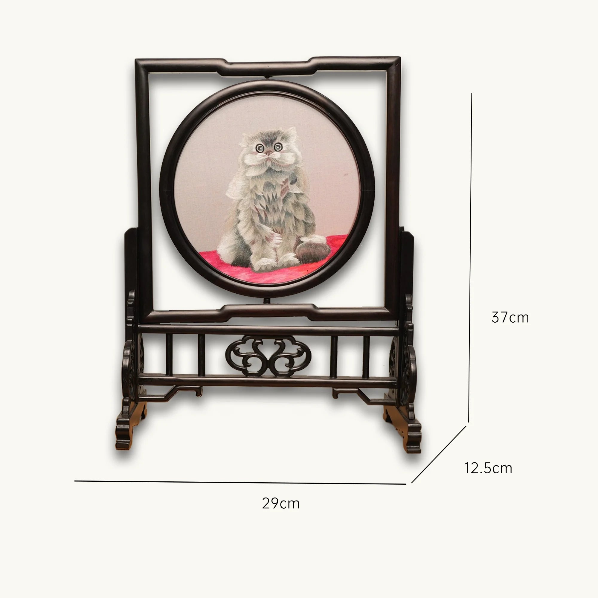 Double-sided embroidery of a fluffy grey cat sitting on a red cushion in a round frame within a rectangular hardwood screen stand with scroll-carved base