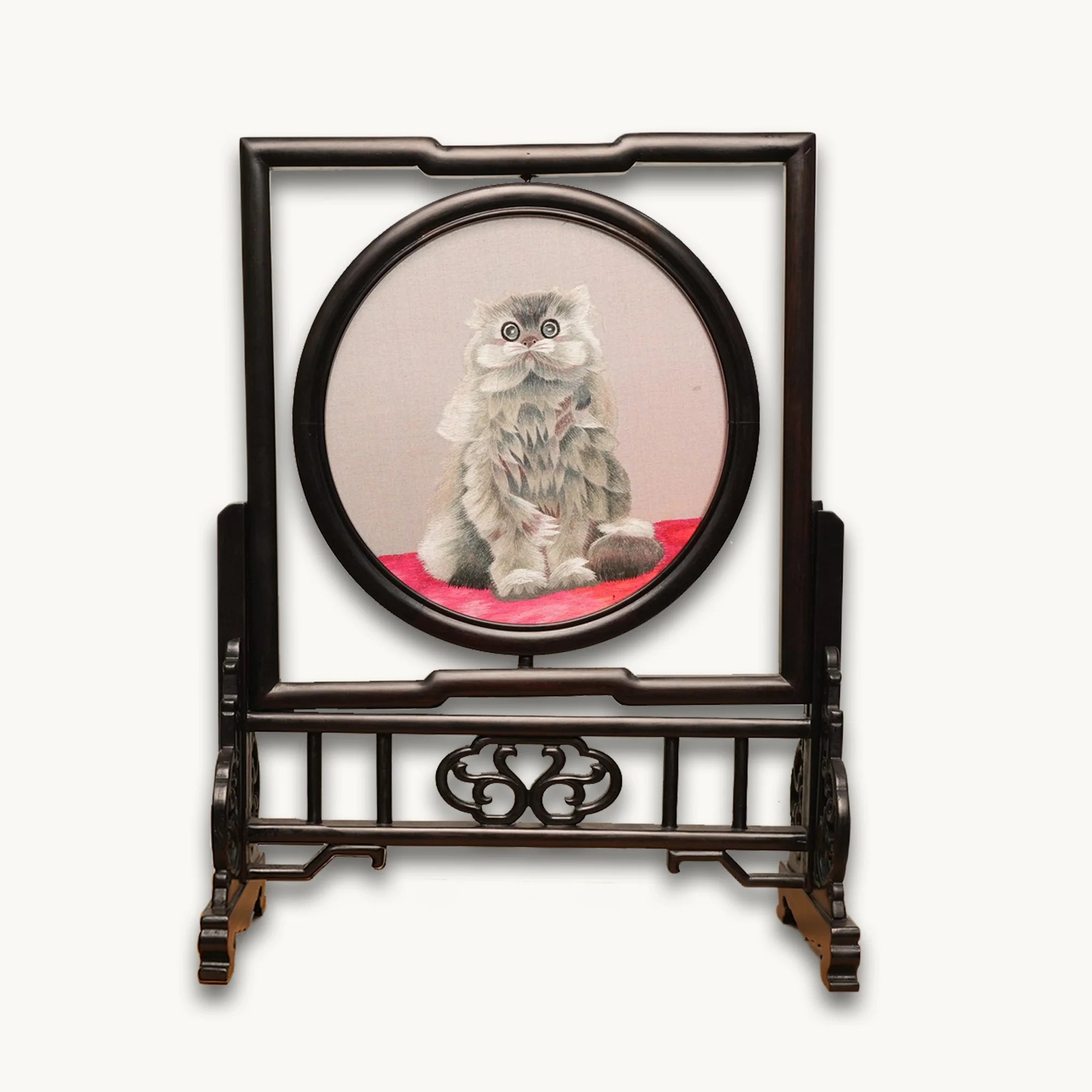 Double-sided embroidery of a fluffy grey cat sitting on a red cushion in a round frame within a rectangular hardwood screen stand with scroll-carved base