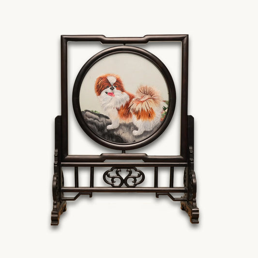 Double-sided embroidery of a brown and white Pekingese dog standing on a rock in a circular frame within a rectangular hardwood screen stand