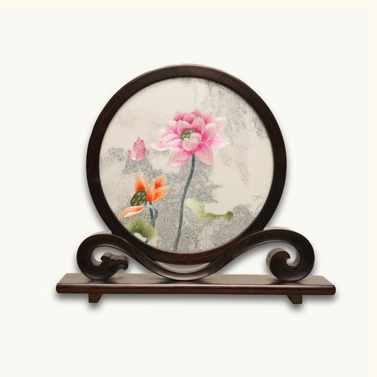 Double-sided embroidery of pink and orange lotus blossoms with green leaves in a round dark hardwood frame on a scroll-carved wooden stand