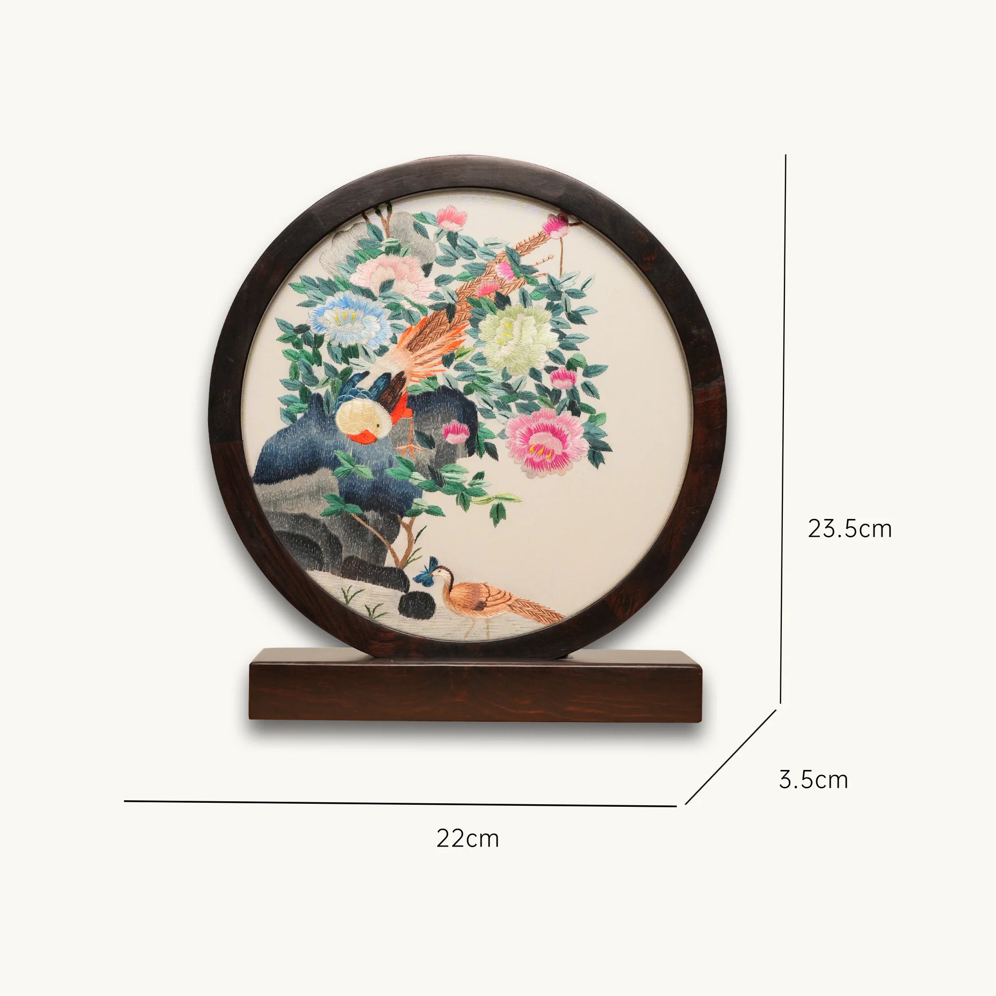 Double-sided embroidery of a golden pheasant on a rock surrounded by colorful peonies in a round dark wood frame on wooden stand