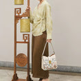Load image into Gallery viewer, Woman carrying a luxury Chinese embroidery shoulder bag with traditional geometric patterns, inspired by oriental craftsmanship and modern Chinese minimalist fashion
