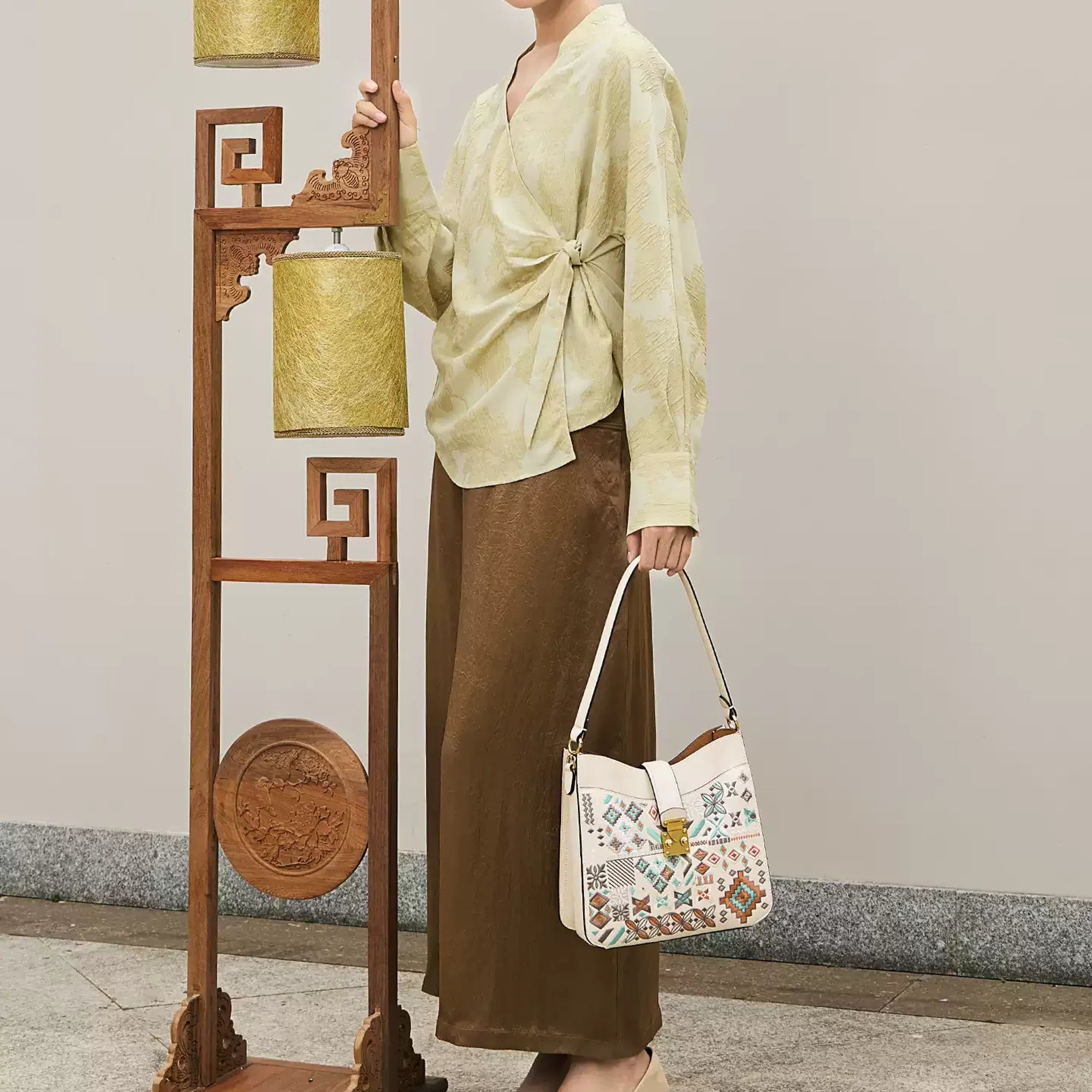 Woman carrying a luxury Chinese embroidery shoulder bag with traditional geometric patterns, inspired by oriental craftsmanship and modern Chinese minimalist fashion