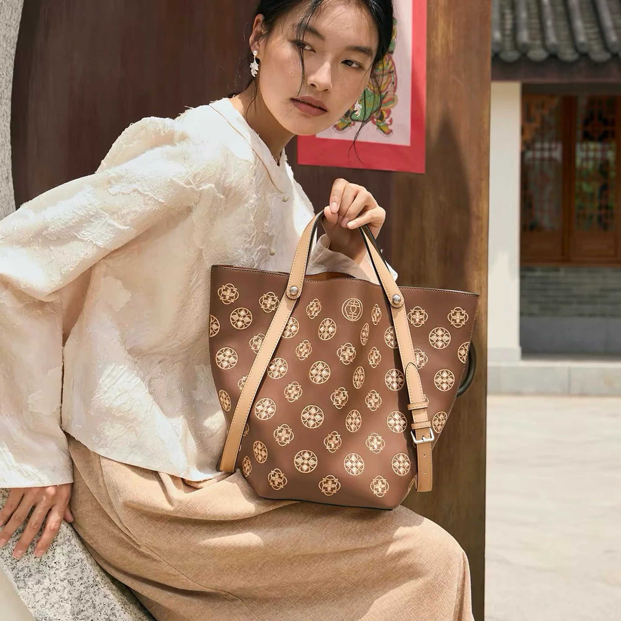 Chinese embroidery luxury tote bag featuring Tang Dynasty inspired Baoxiang flower pattern, a modern oriental leather handbag carried by a woman in traditional Chinese style setting