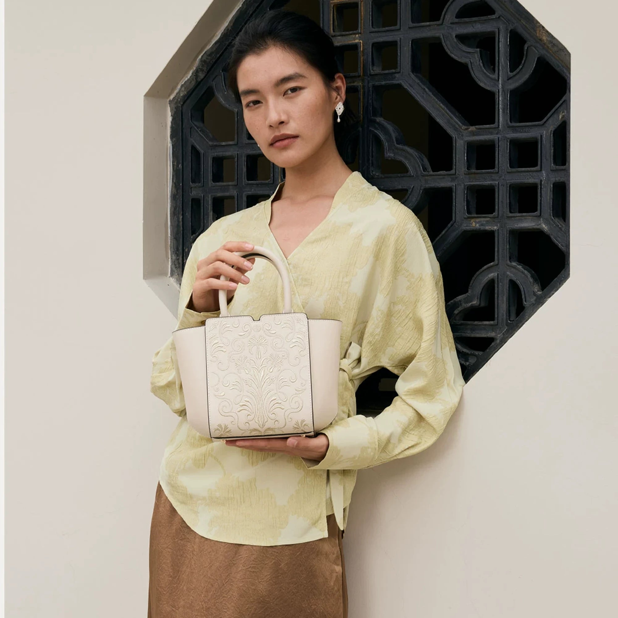 SinoCrafted Suzhou embroidery handbag with elegant floral patterns, held by a woman in a modern Chinese-inspired setting.