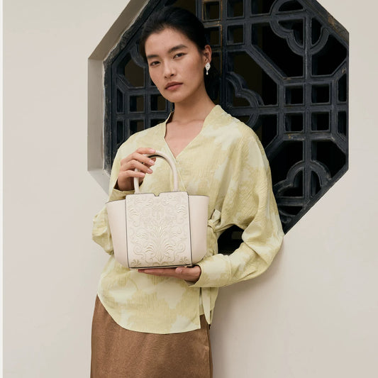SinoCrafted Suzhou embroidery handbag with elegant floral patterns, held by a woman in a modern Chinese-inspired setting.