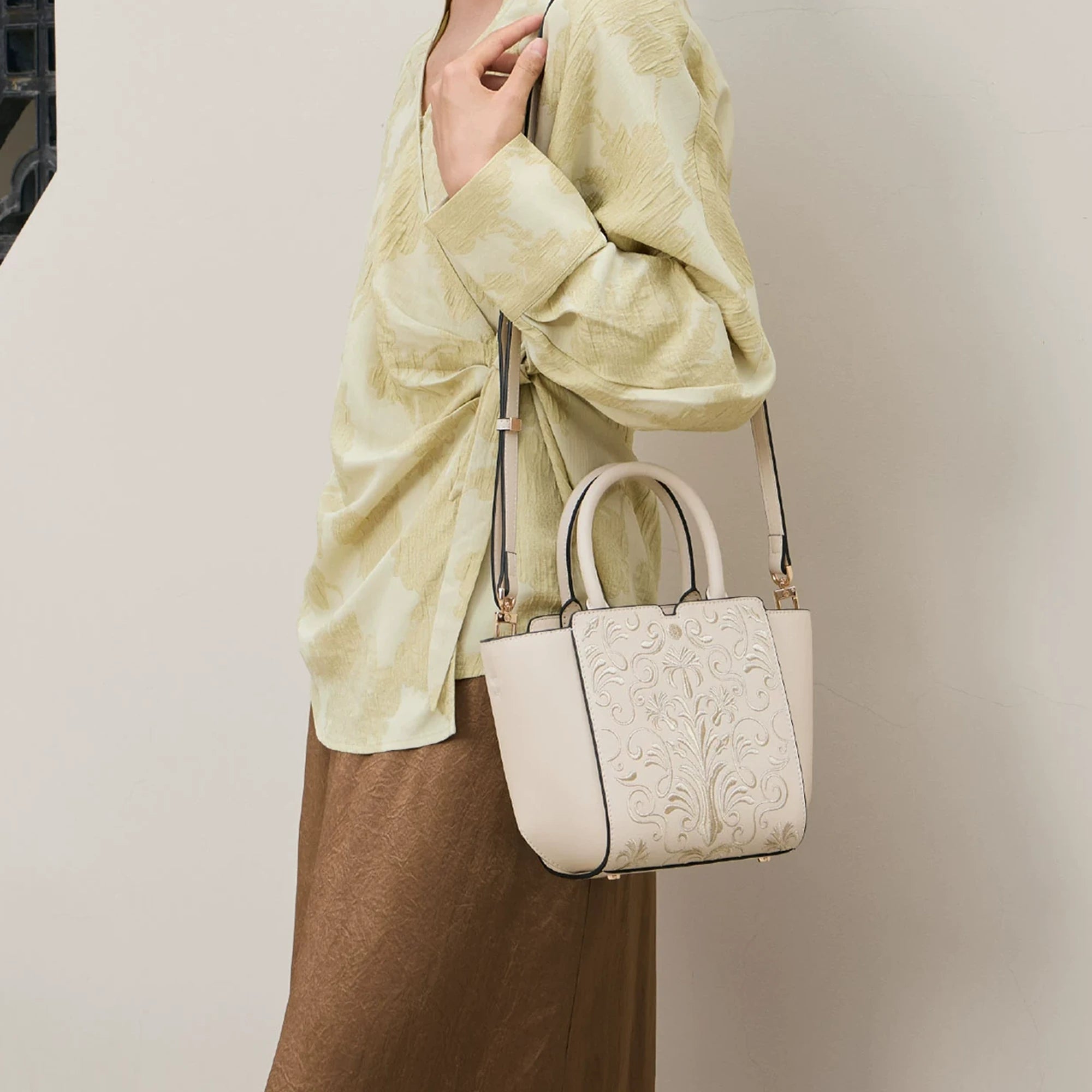 SinoCrafted Suzhou embroidery crossbody handbag with delicate floral patterns, styled by a woman in a modern Chinese-inspired setting.