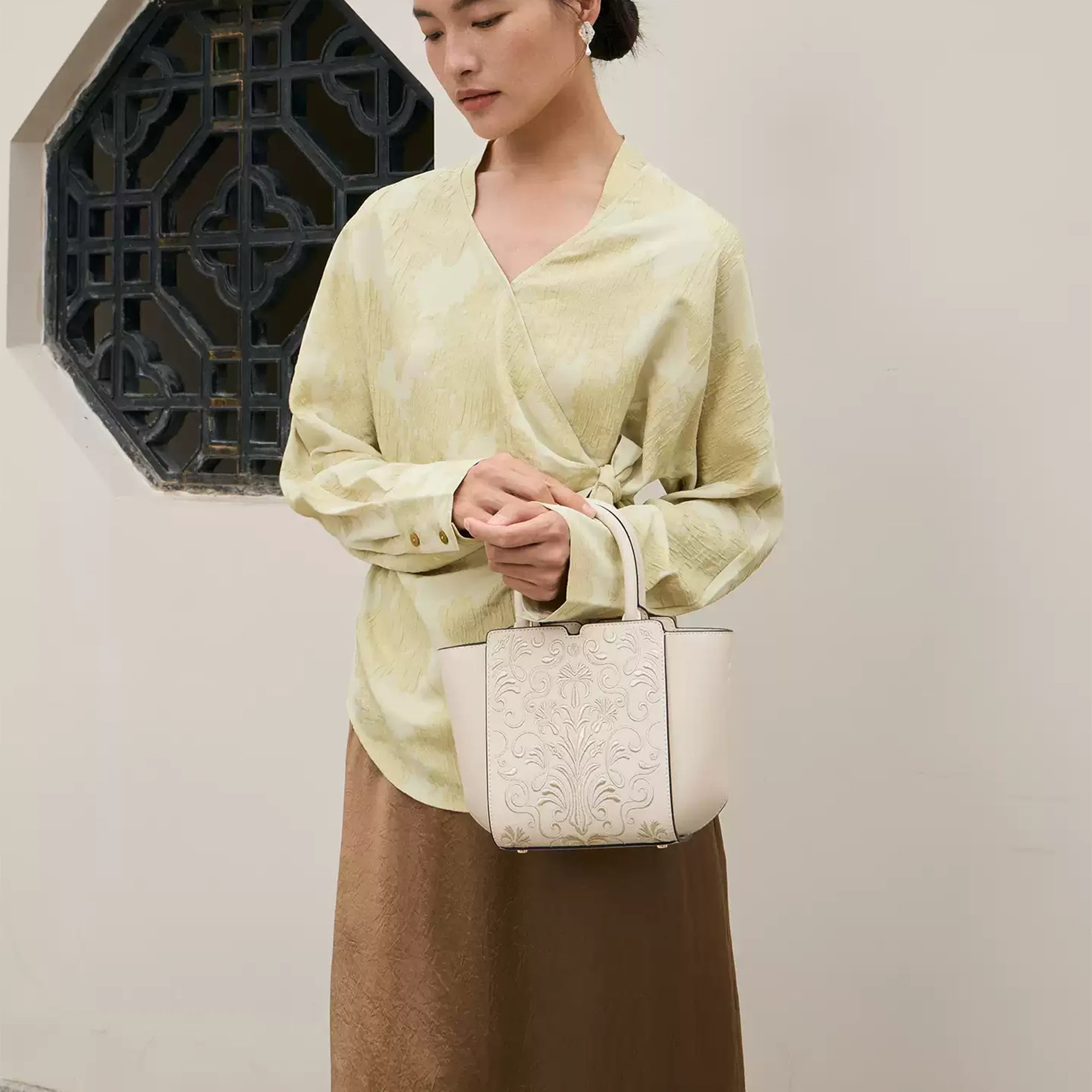 SinoCrafted Suzhou embroidery handbag with elegant floral patterns, held by a woman in a modern Chinese-inspired setting.